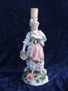 Candelholder porcelain of woman with flower basket and vines and flowers all around.